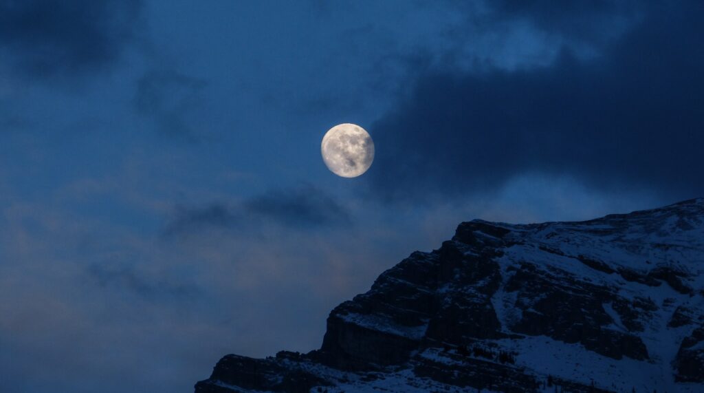 Moon behind clouds and mountain