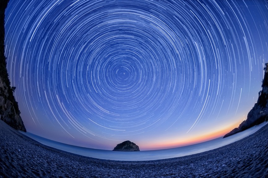 Star trails in night sky over beach